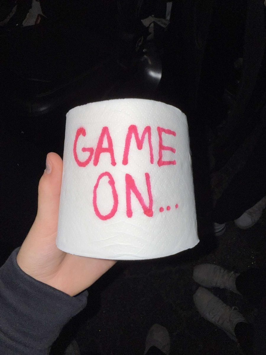 Preparing for a night of toilet papering, the volleyball team writes a message on one of the rolls.